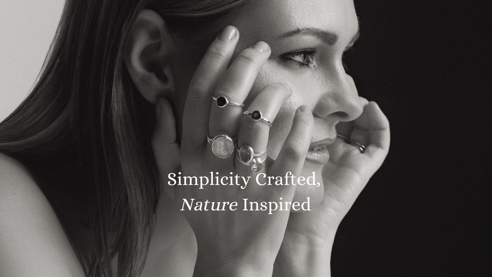 Close-up of a woman wearing minimalist, nature-inspired silver rings with natural stones, showcasing simplicity and elegance. The text reads: 'Simplicity Crafted, Nature Inspired.'