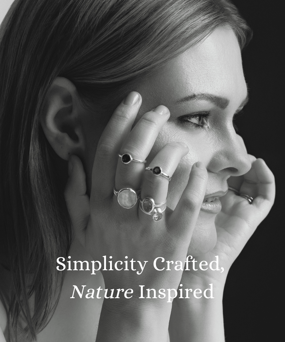 Close-up of a woman wearing minimalist, nature-inspired silver rings with natural stones, showcasing simplicity and elegance. The text reads: 'Simplicity Crafted, Nature Inspired.'